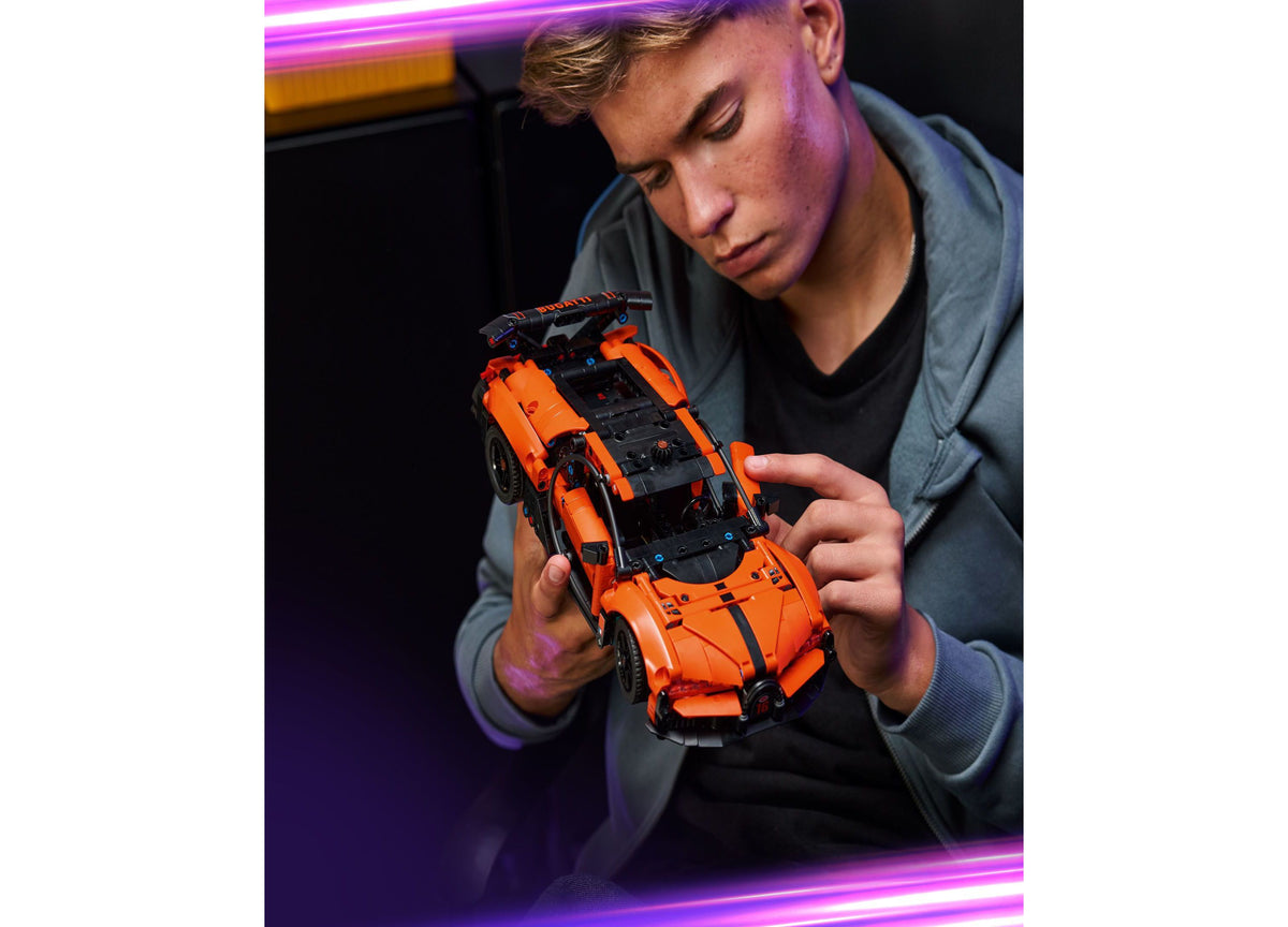 Orange and black LEGO Technic Bugatti Chiron Pur Sport hypercar model held by person in gray hoodie