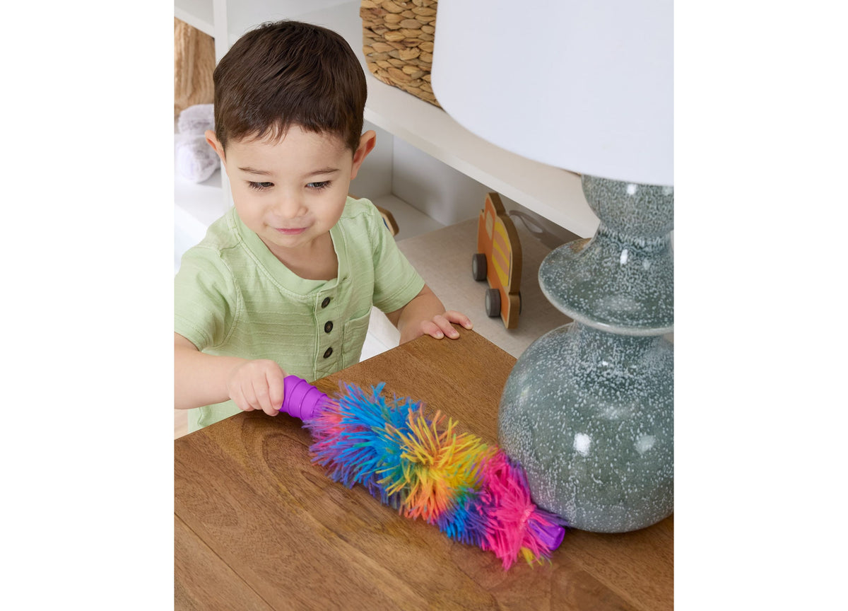 Toddler in green shirt using Fisher-Price Laugh & Learn 2-in-1 Vacuum with colorful rainbow bristles