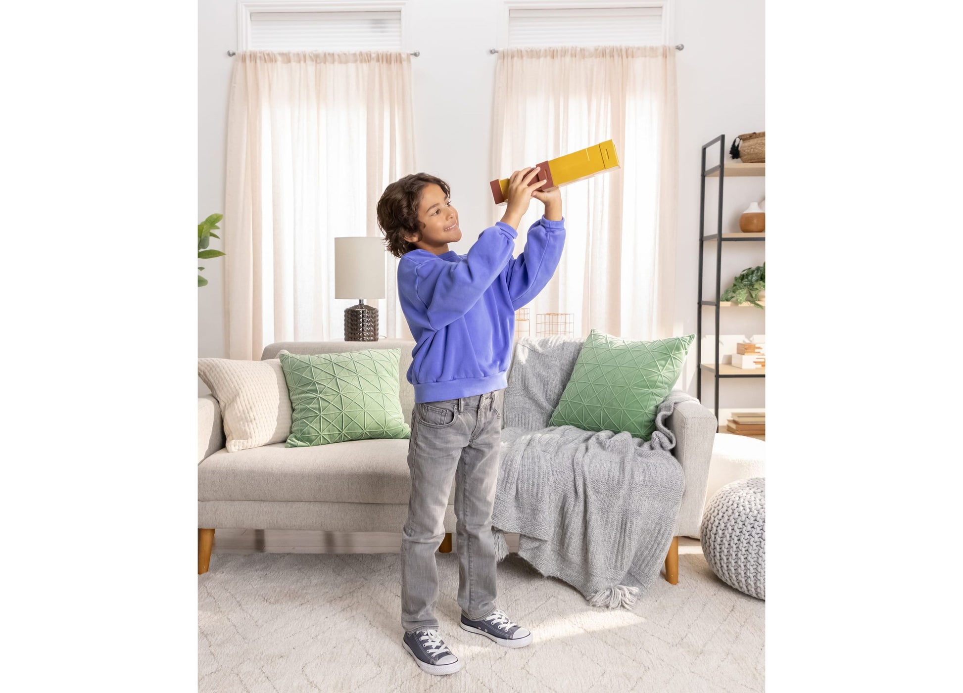 Boy holding yellow and red Minecraft Pixel Spyglass toy while playing in living room