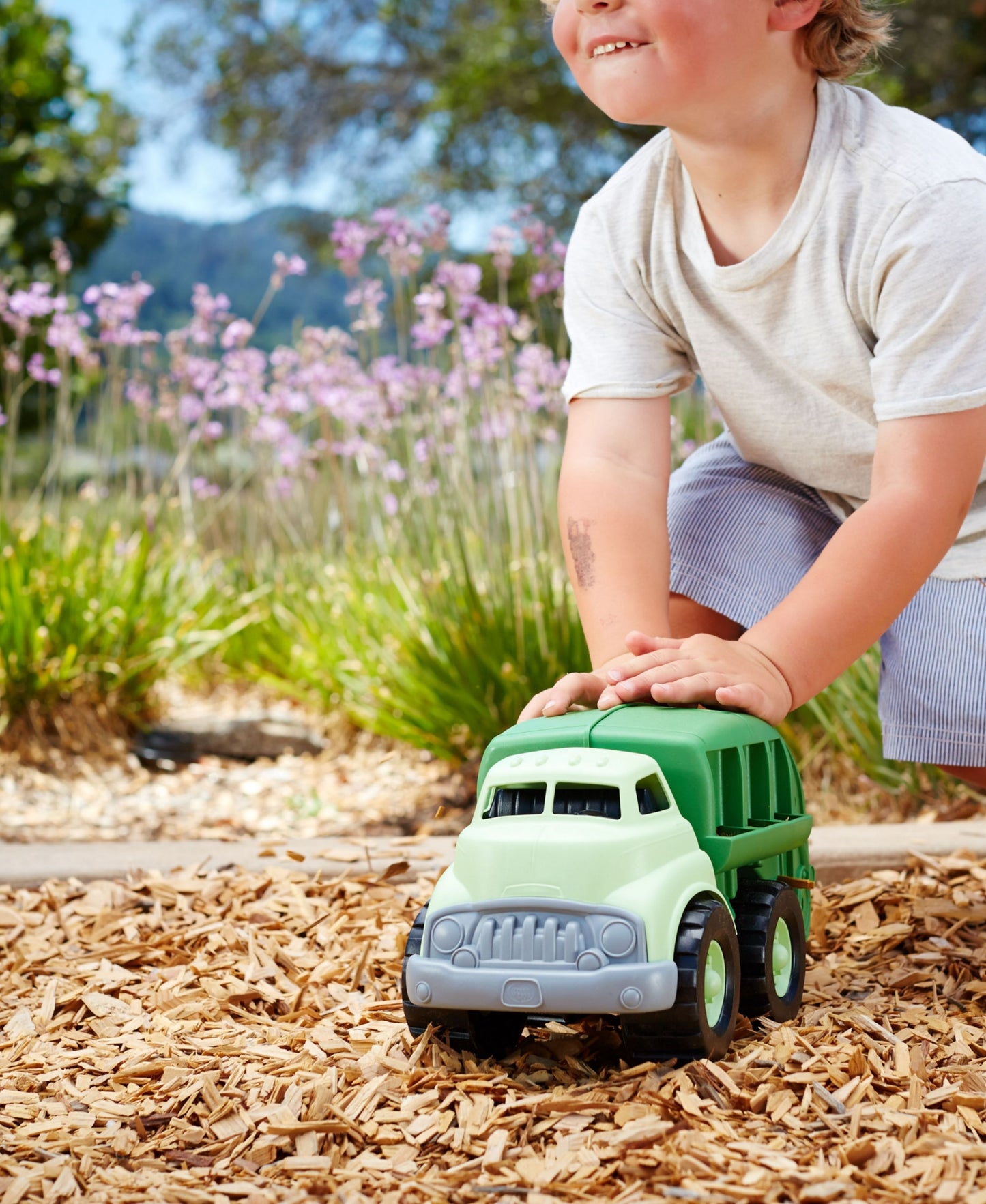 Green Toys Recycling Truck toy in light green and dark green, held by child in garden