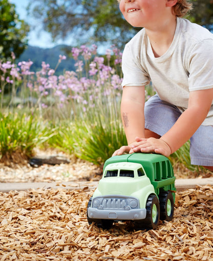 Green Toys Recycling Truck toy in light green and dark green, held by child in garden