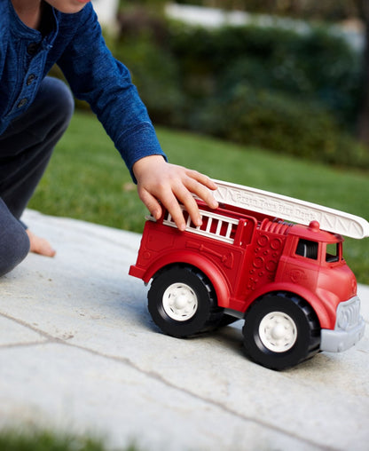 Green Toys Fire Truck red toy with white wheels held by child