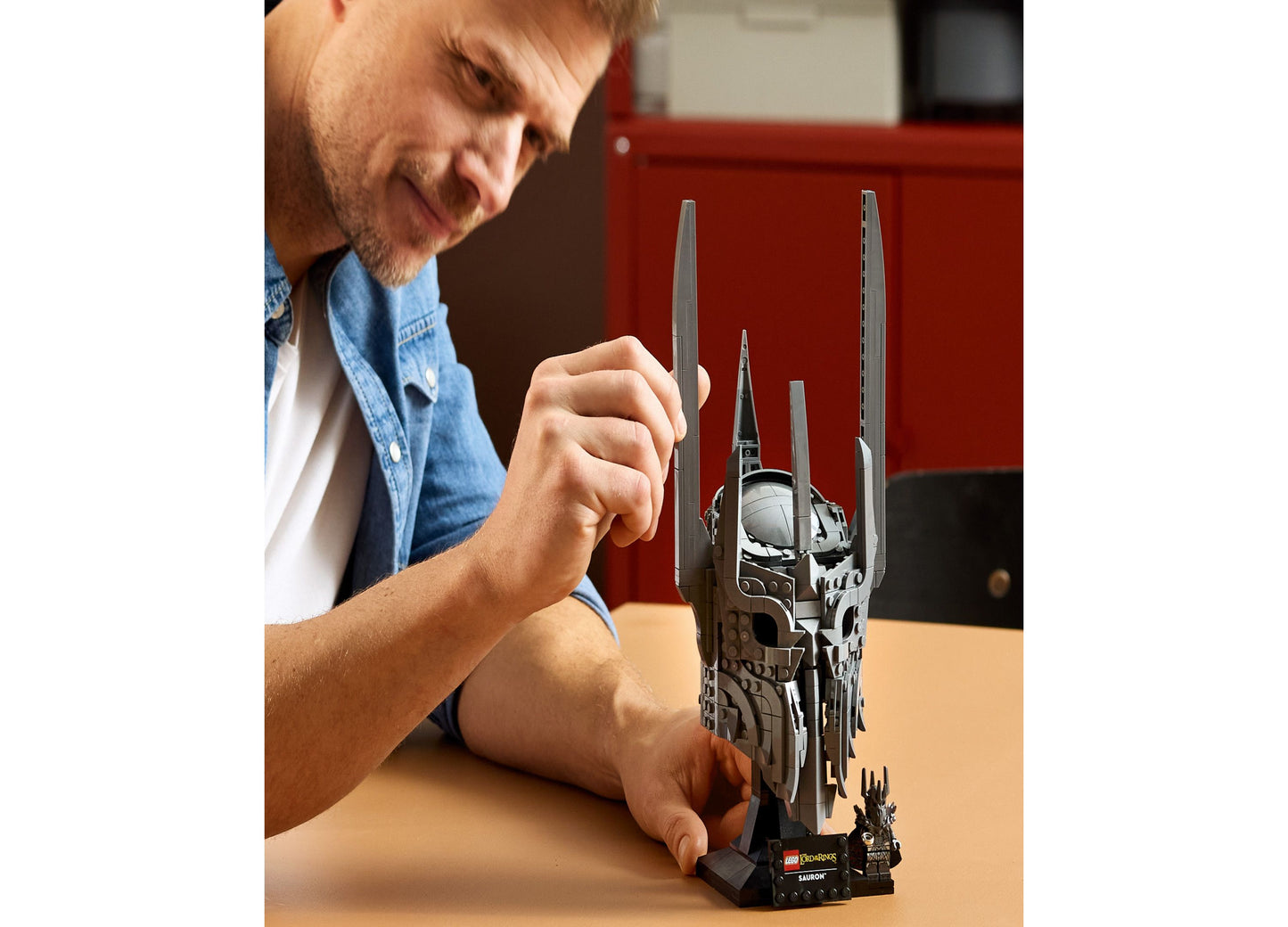 Man assembling LEGO Icons Sauron's Helmet Display Model Kit with dark gray and black pieces