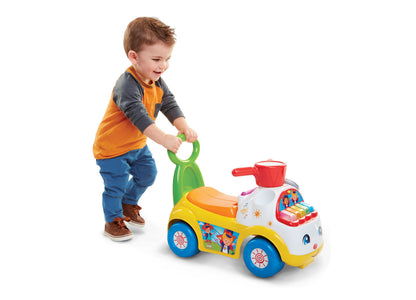 Fisher-Price Little People Music Parade Ride-On toy with lights and sounds in yellow, blue, and red, shown with toddl...