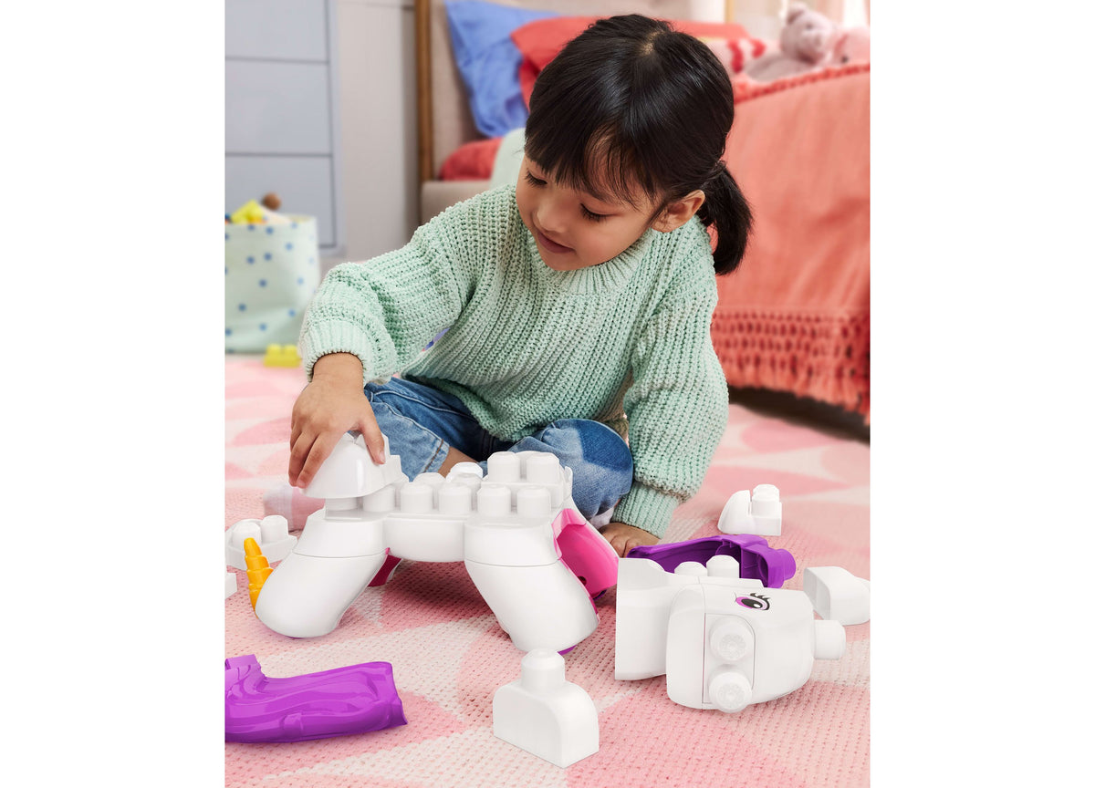 Child playing with Mega Bloks Build & Enchant Unicorn 26-Piece Building Set, white and purple chunky blocks arranged ...