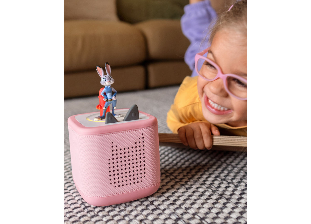 Pink Tonies Disney Zootopia figurine with rabbit character on top, displayed next to smiling child wearing glasses