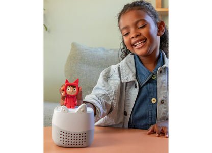 Girl smiling at white Toniebox Lite speaker with red Rubie Creative Tonie character on top