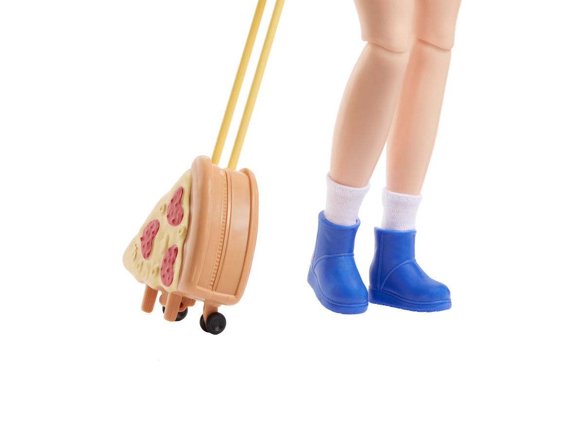 Barbie Dream Besties Renee doll wearing blue boots with white socks, holding a peach-colored carry-on suitcase with g...