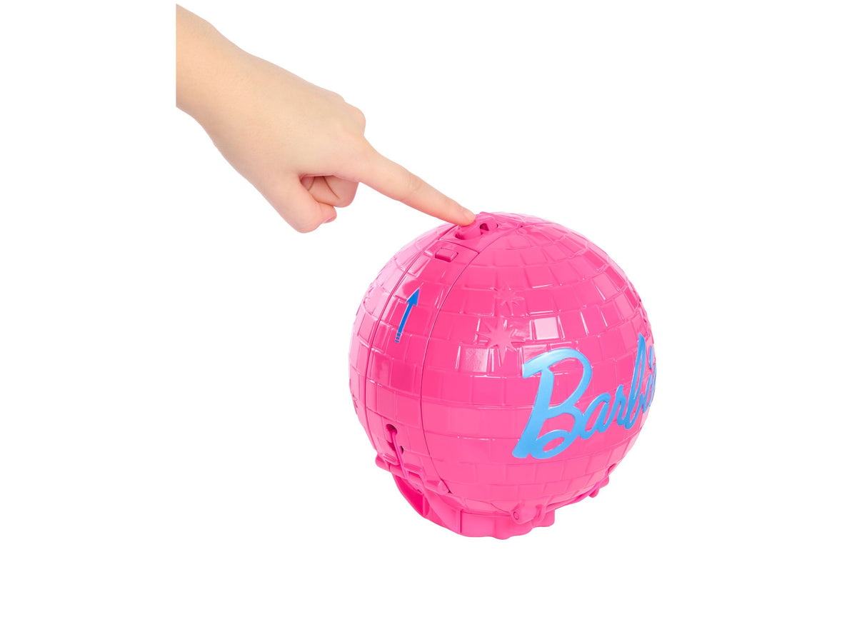 Barbie Roll & Reveal Pop Star doll in bright pink spherical ball packaging with blue Barbie logo text, shown being he...