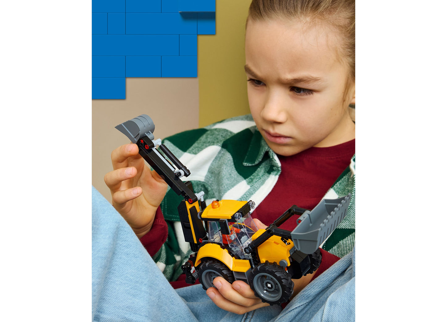 Child playing with LEGO City Backhoe Loader 60480 yellow and black construction vehicle toy
