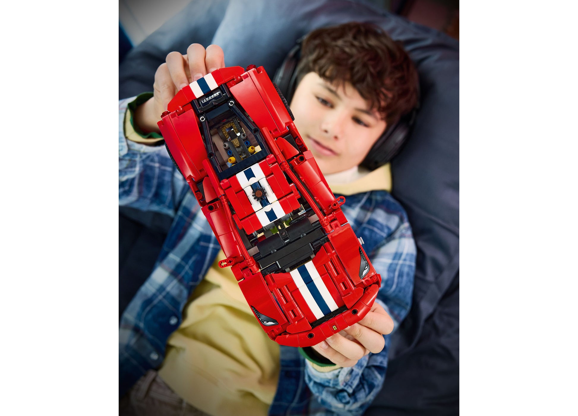 Child holding red LEGO Technic Ferrari 488 PISTA building set with white racing stripes