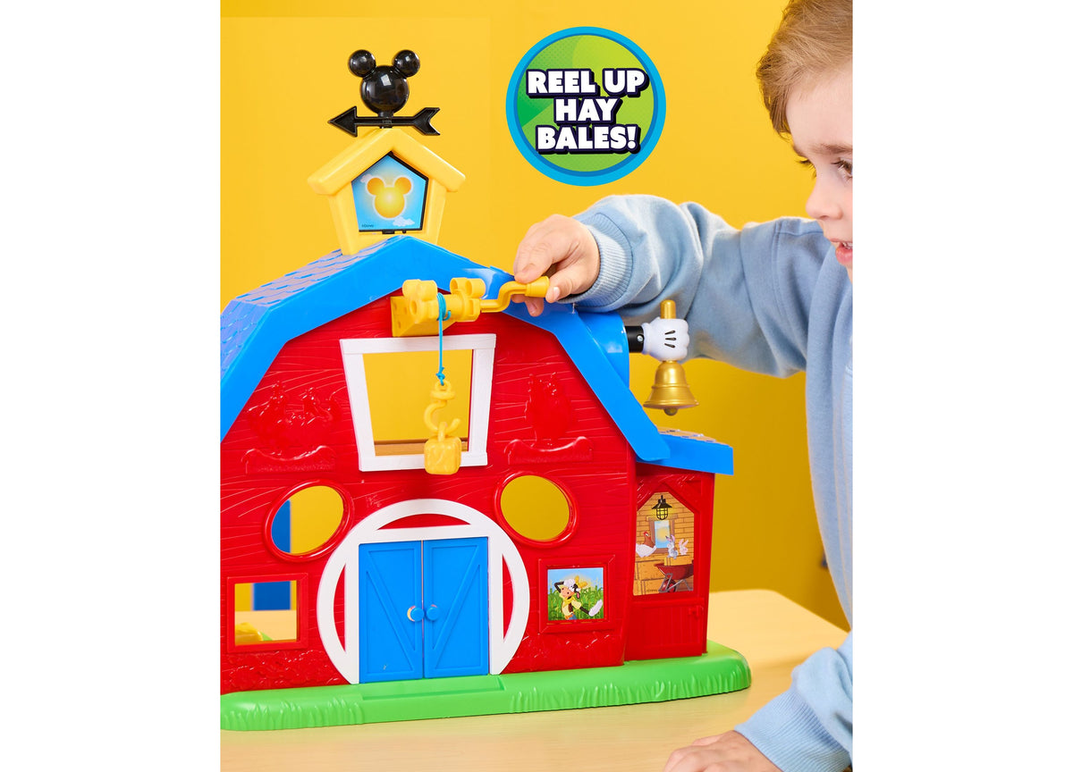 Mickey Mouse Barnyard Fun playset with red barn, blue doors, and child's hand pulling yellow hay bale mechanism