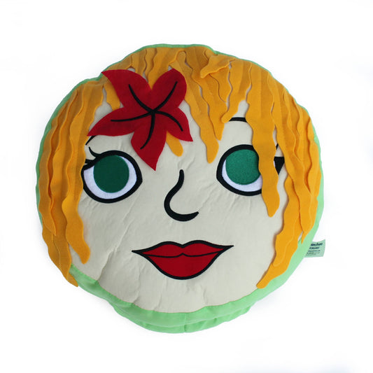 Round plush character with golden yellow wavy hair, green circular eyes with black lashes, red lips, and a red flower hair clip on a white cream-colored face wi