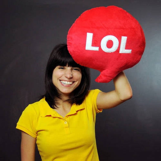 Child modeled by girl holding large red plush speech bubble pillow with white "LOL" text