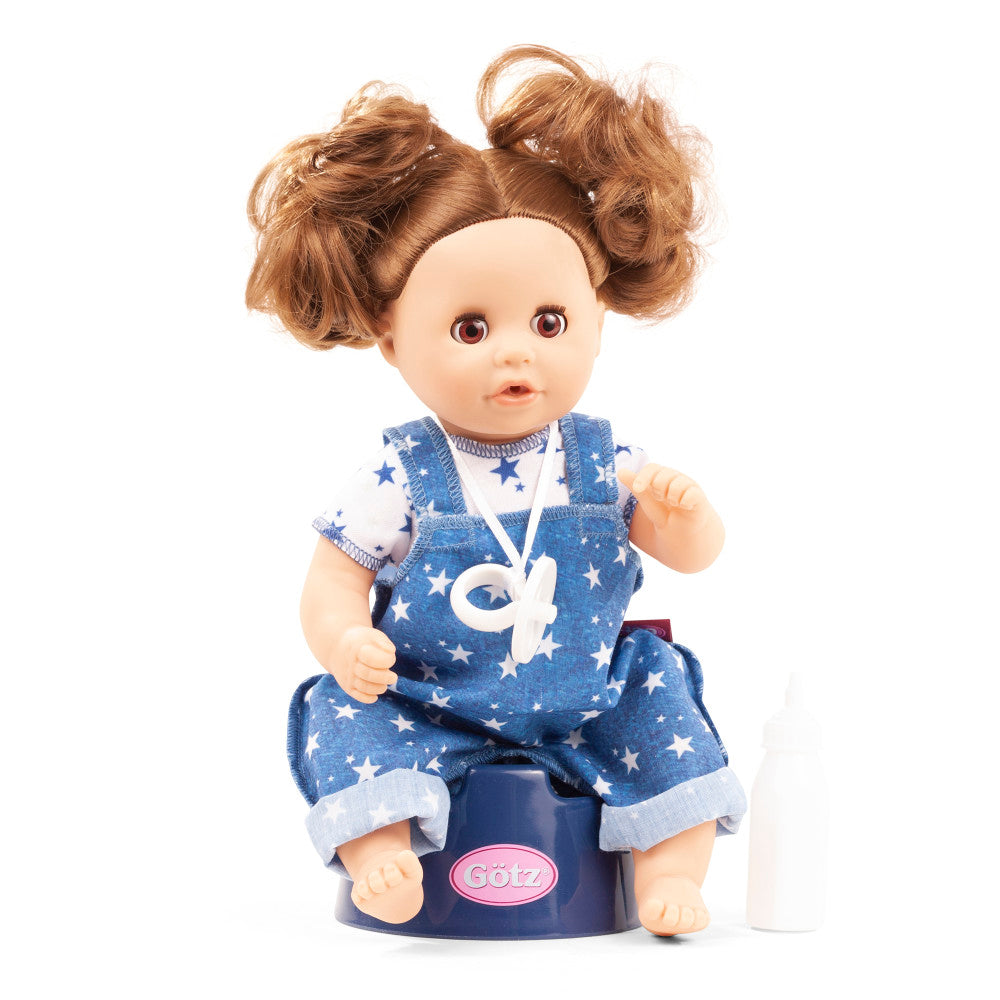 Gotz Aquini baby doll with brown curly hair in pigtails, wearing blue star-print overalls and white star-print shirt, seated on navy potty trainer with pink Got