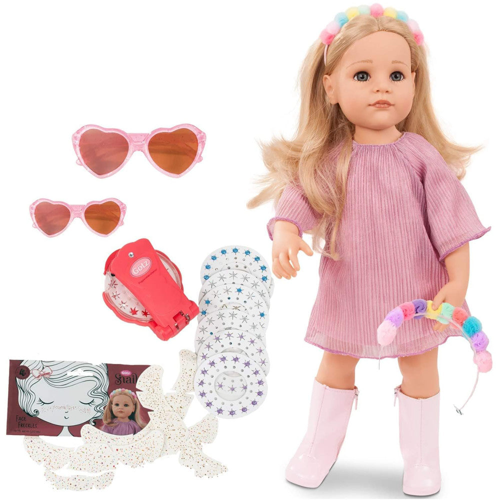 Gotz Hannah doll with blonde hair and rainbow hair clips, wearing pink ribbed dress and pink boots, shown with accessories including two pairs of heart-shaped s