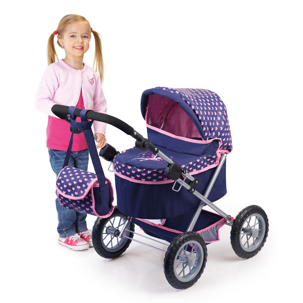 Child modeled by a girl pushing navy and pink polka dot doll pram stroller with canopy hood and shoulder bag