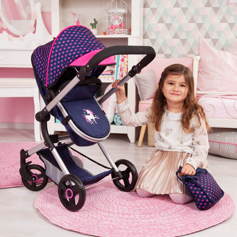 Modeled by a child with navy and hot pink polka-dot doll stroller featuring black handles and unicorn design on seat, shown in pink bedroom setting