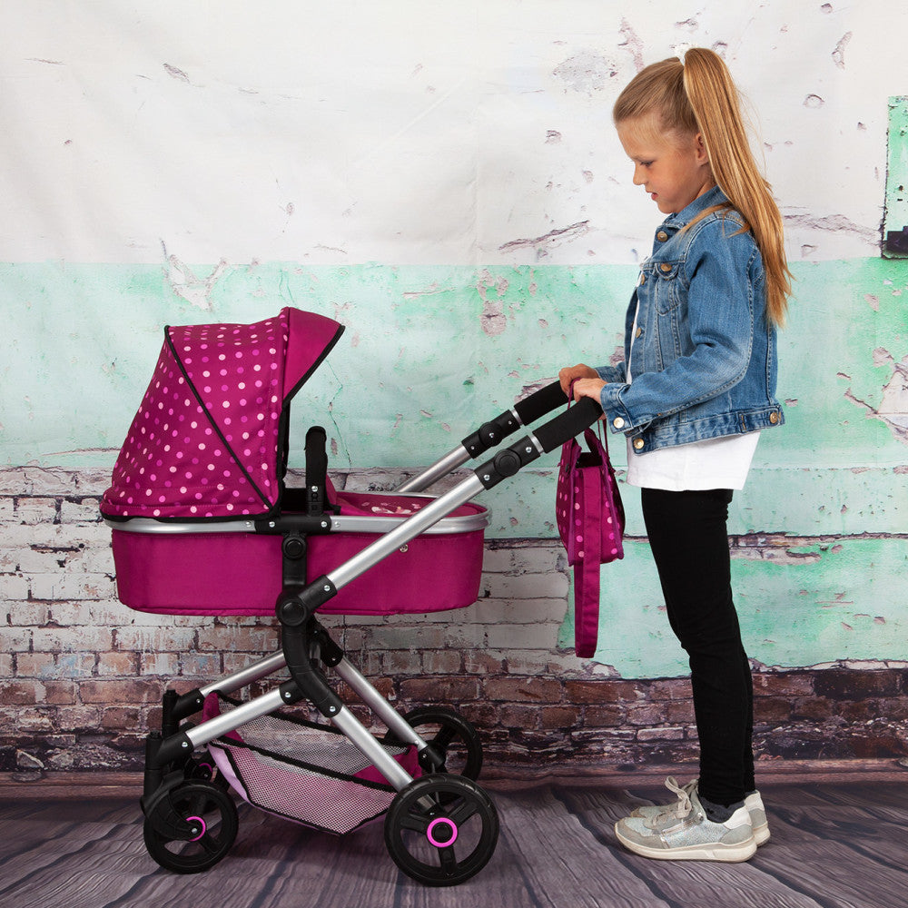 Child modeled by a girl with a magenta and polka-dot doll pram stroller with silver handles on wheels