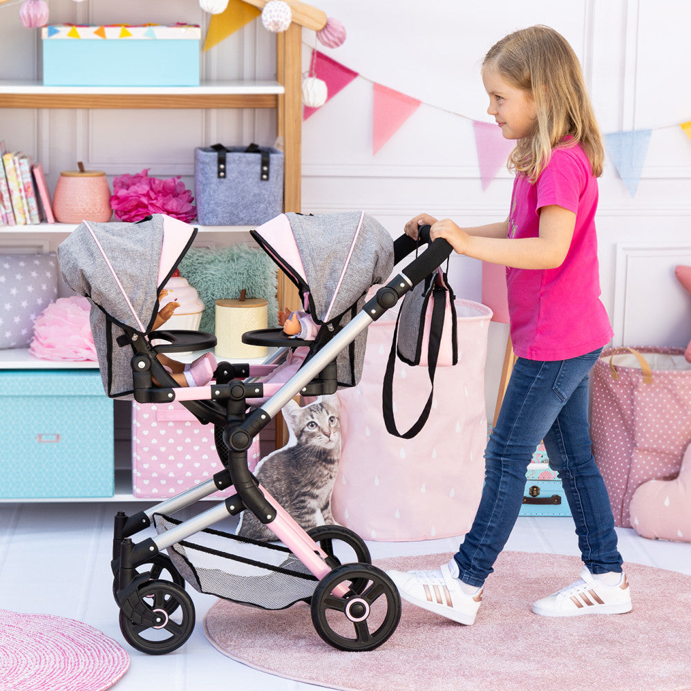 Child modeled by a girl in pink shirt pushing a dual-seat doll pram with gray fabric canopies and black frame in a playroom setting