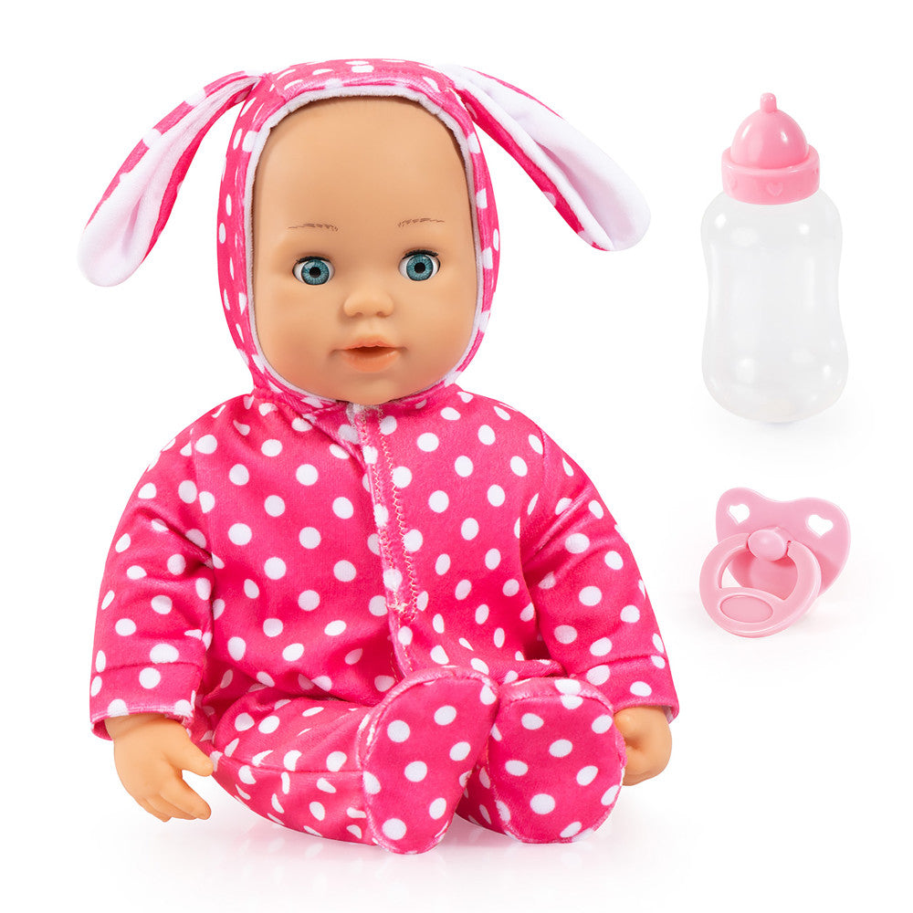 Baby doll with blue eyes wearing pink and white polka dot bunny onesie and matching bunny hood, shown with included bottle and pacifier accessories