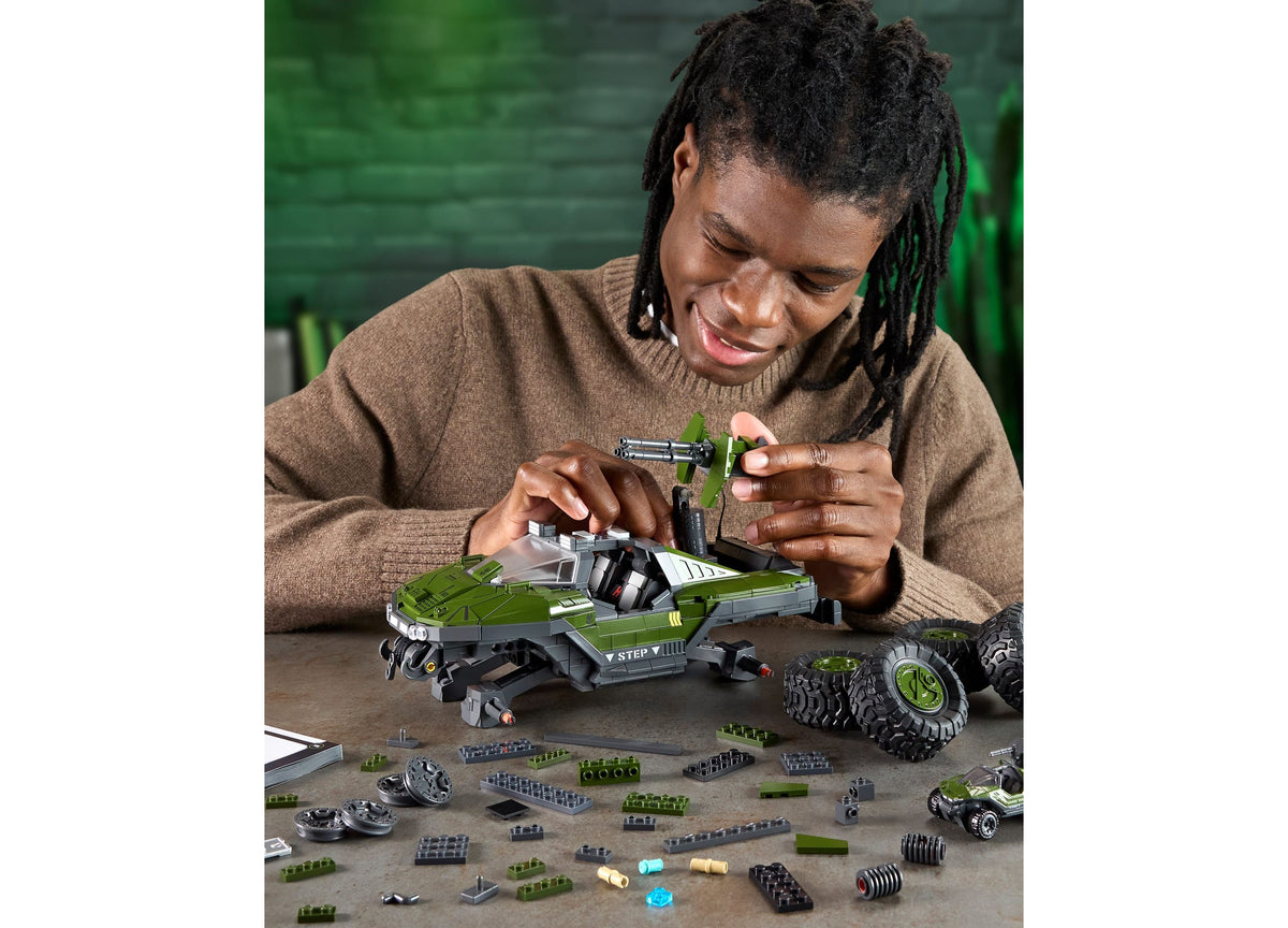Hands assembling green and gray UNSC M12 Warthog building set with cannon detail and separate die-cast vehicle