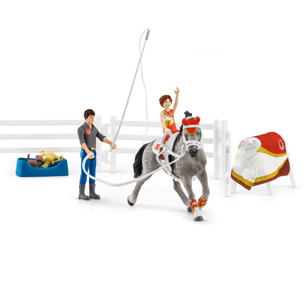 Schleich Horse Club Mia's Vaulting Set with gray horse, two child figures in riding outfits, one adult figure with lasso, white fence, blue hay bin, and red-and
