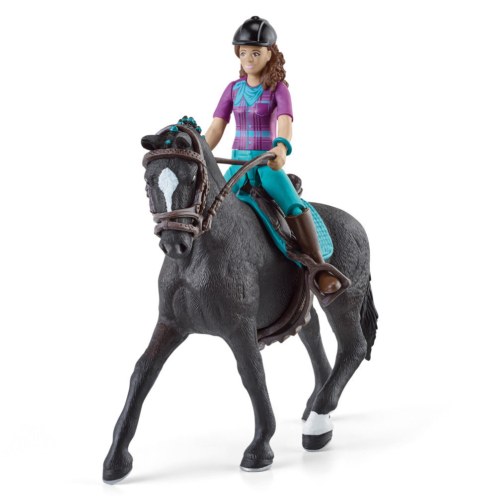 Doll with brown curly hair wearing black helmet, purple and turquoise outfit on gray horse with brown saddle and turquoise tack