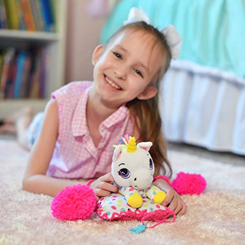 Child modeled by a young girl in pink playing with a white unicorn plush toy with yellow accents and pink fluffy pom-poms on a carpeted floor