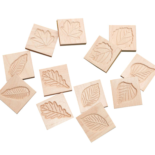 Twelve wooden tiles with carved leaf designs in various shapes, displayed on a white background