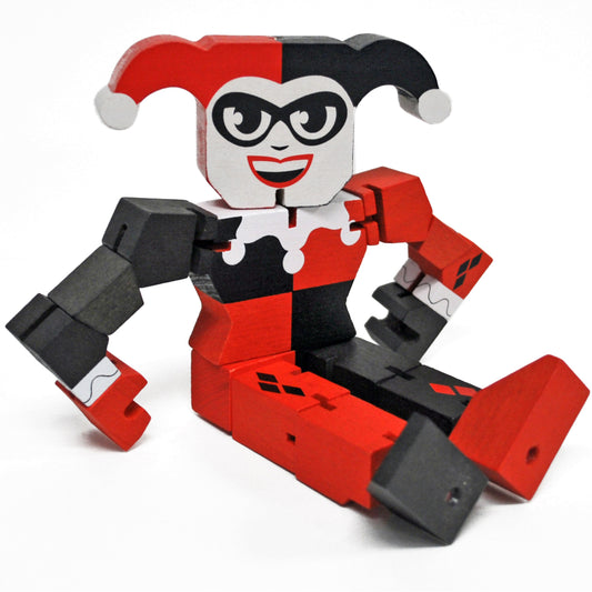 Harley Quinn articulated wooden action figure with red and black color-blocked body, white face with black mask and red smile, jester hat with gray pom-poms, an