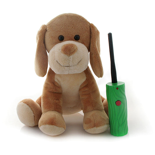 Tan and cream plush puppy toy with long floppy ears, black eyes, and embroidered smile, sitting next to a green interactive remote control with black antenna
