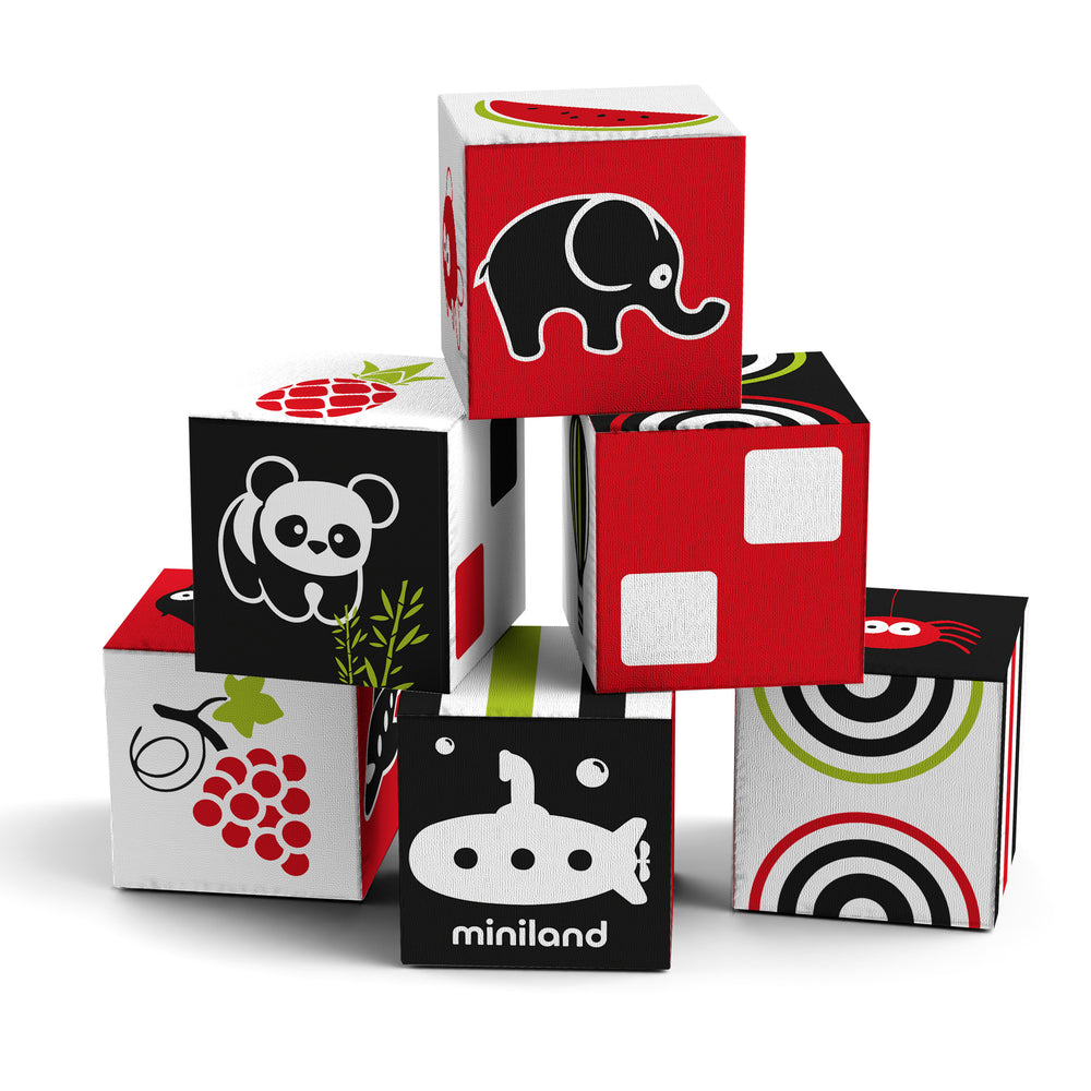 Six soft fabric cubes with contrasting black, red, white, and lime green colors featuring animal and pattern designs including elephant, panda, submarine, and g