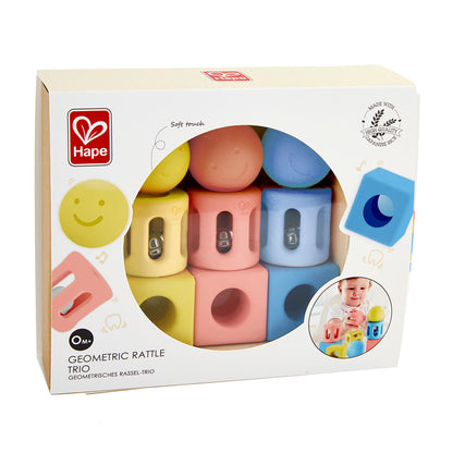 Hape Geometric Rattle Trio boxed set with yellow, pink, and blue stacking blocks featuring soft-touch surfaces and built-in rattles, displayed on packaging show
