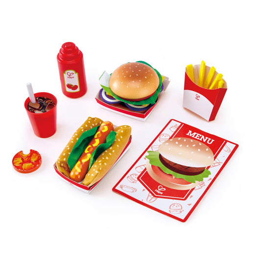 Hape wooden fast food playset with hamburger, hot dog, french fries, drink cup, ketchup bottle, menu card, and red food containers on white background