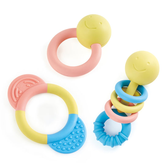 Three colorful baby rattles and teethers with yellow smiley-face tops, pink and blue curved handles, and textured teething surfaces in pastel colors