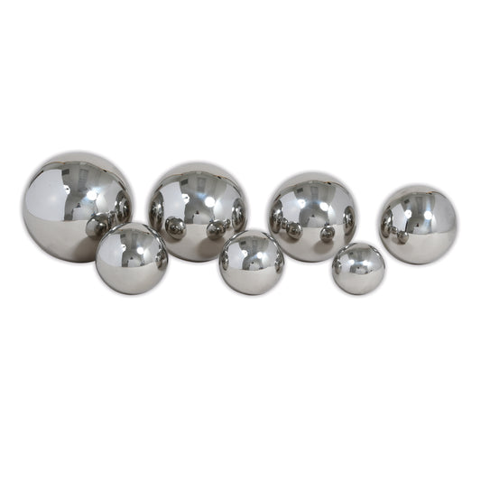 Set of 7 reflective silver metal balls in varying sizes arranged on a white background