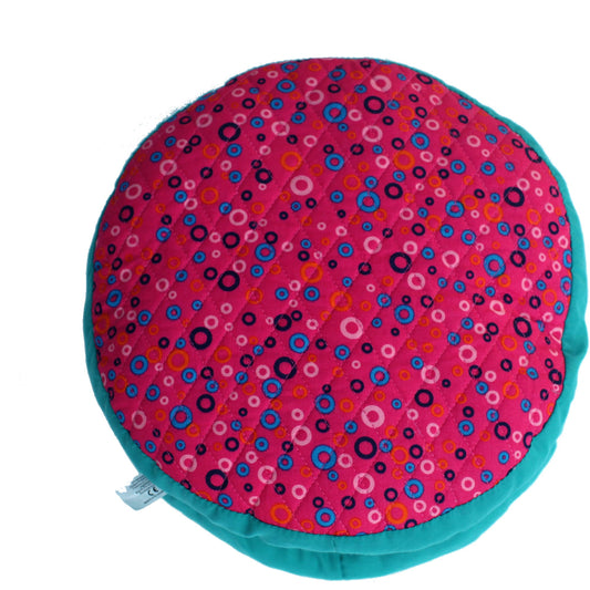 Round plush pillow with hot pink circle-pattern fabric and turquoise trim, shown against plain background