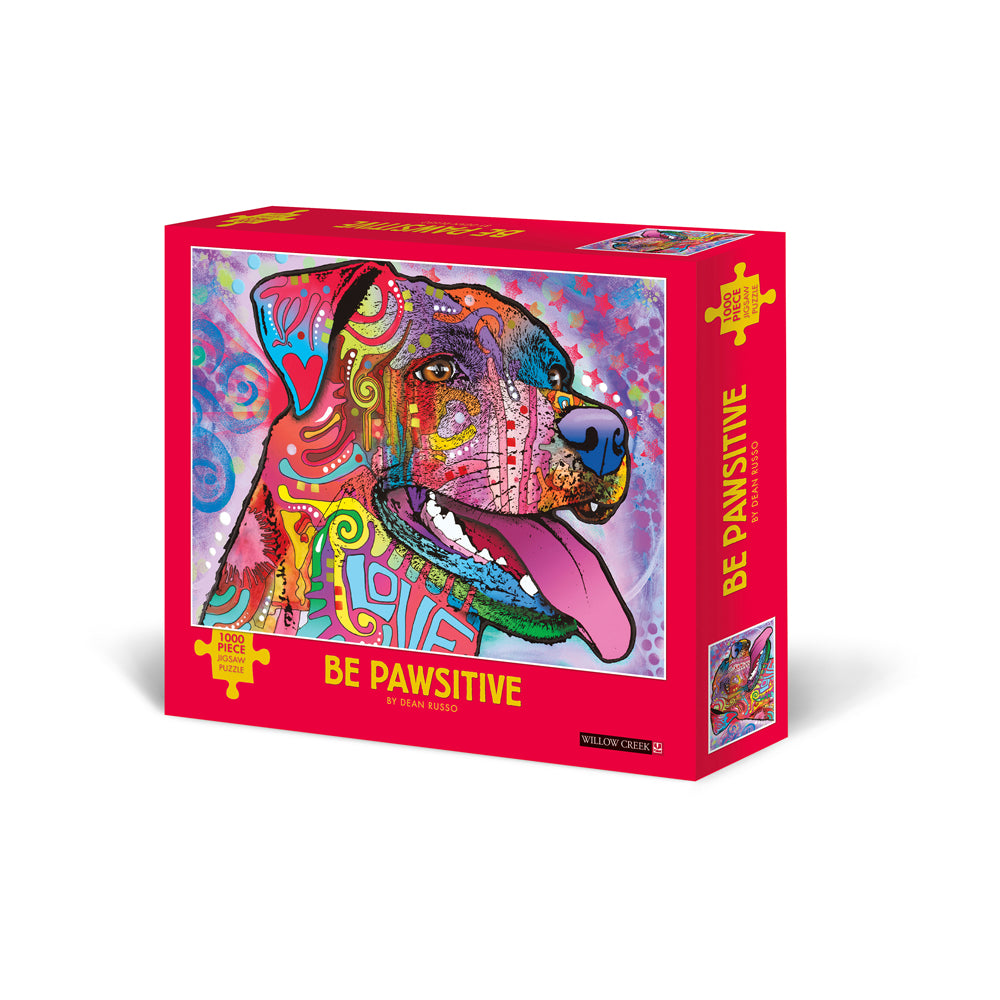 1000-piece jigsaw puzzle box with bright pink packaging featuring colorful pop art dog illustration with intricate patterned design by Dean Russo, titled Be Paw