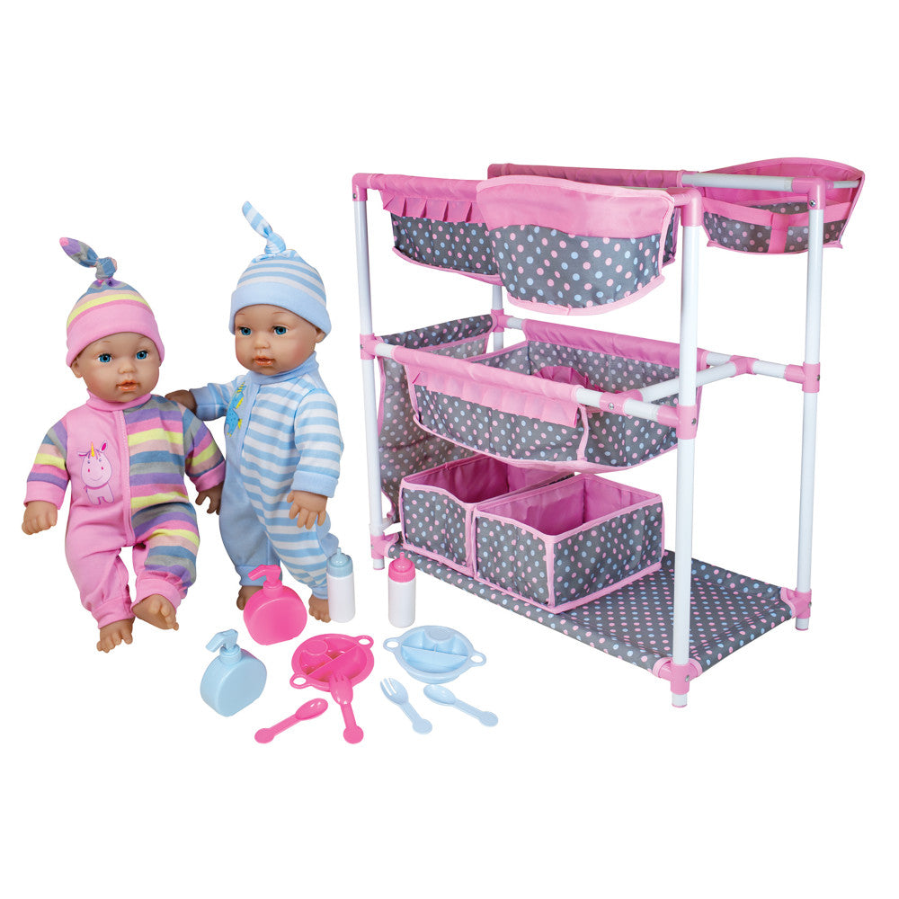 Twin baby dolls with hats and colorful outfits next to a pink and gray storage organizer with multiple baskets, feeding bottles, and play dishes