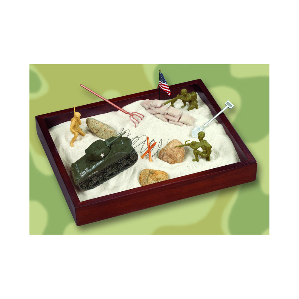 Wooden sandbox with white sand containing miniature military figurines, tank, American flag, rocks, and play accessories on green background