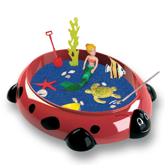 Red ladybug-shaped tabletop sandbox with blue sand, mermaid figurine, sea turtle, fish, starfish, seaweed, shells, shovel, and fishing rod accessories
