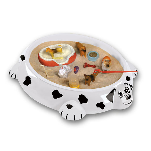 White dalmatian-shaped sandbox toy with black spots containing sand, miniature animals, shells, and accessories for tabletop play
