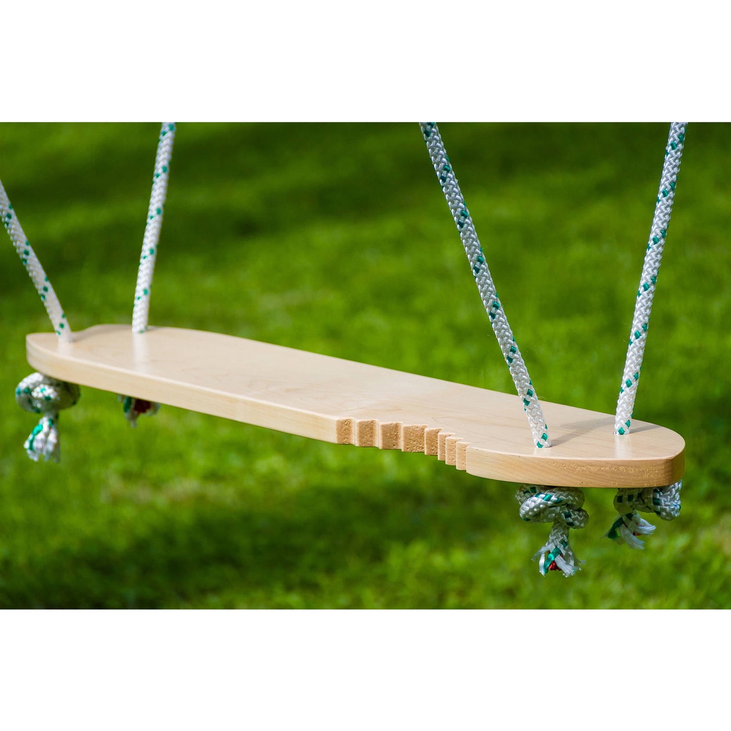 Wooden swing seat with rope handles against green grass background