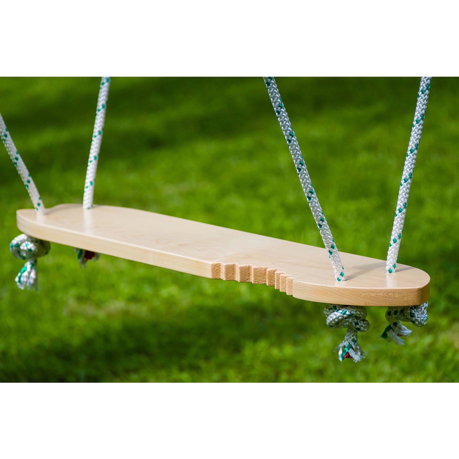 Wooden swing seat with rope handles against green grass background