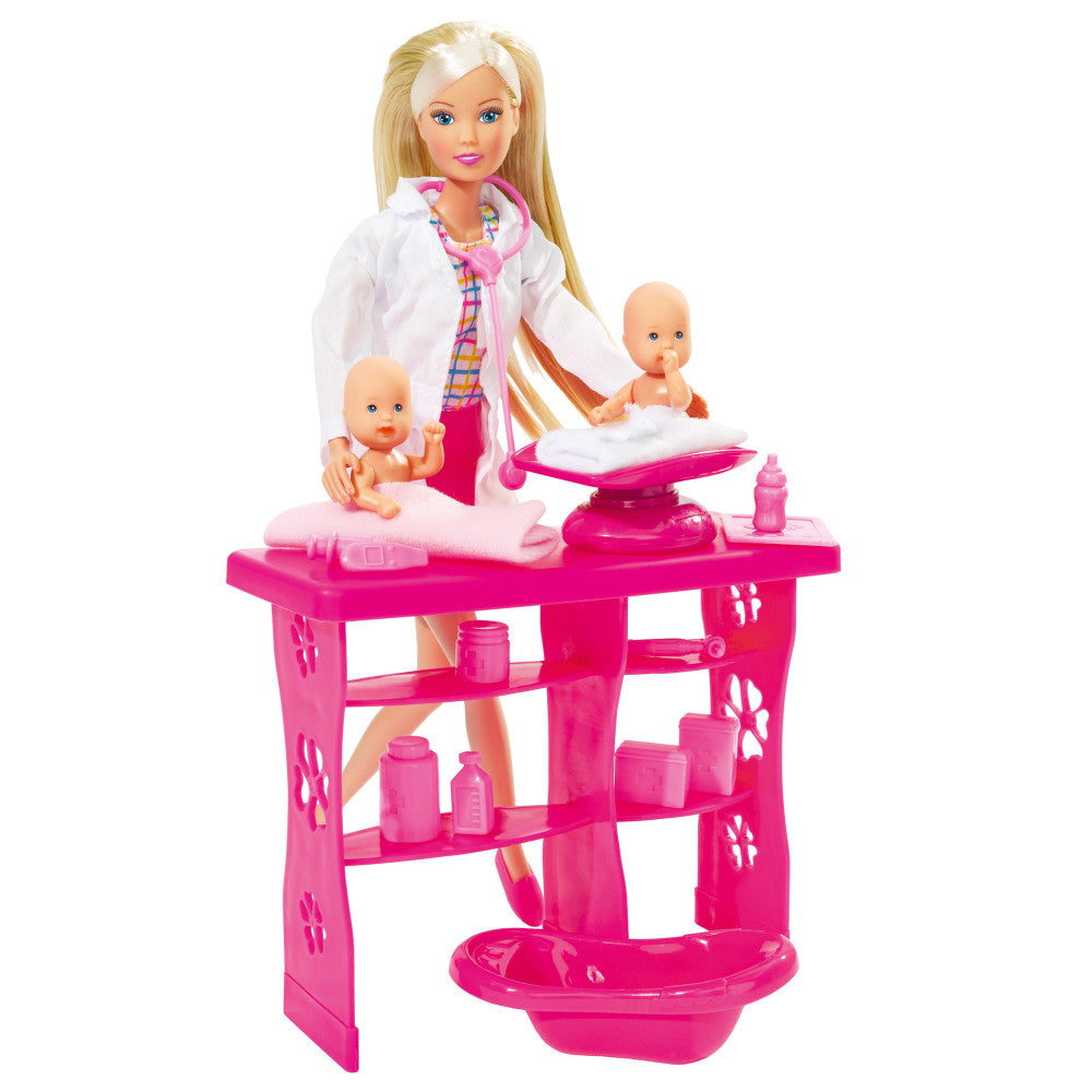 Steffi Love doll with blonde hair in white coat standing at bright pink medical examination station with two baby dolls and accessories