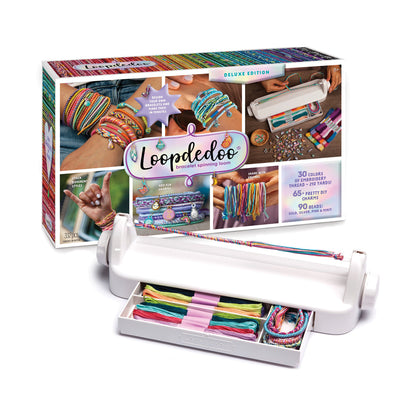 Loopdedoo bracelet spinning loom deluxe edition kit with white machine, colorful embroidery threads, beads, and instructional packaging showing finished rainbow
