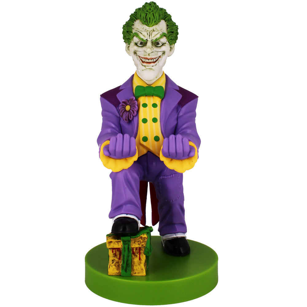 Joker character figure in purple suit and yellow shirt with green hair, holding purple gloved fists, standing on green base with gift box