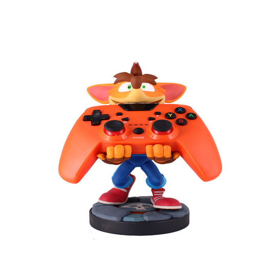 Crash Bandicoot character figure with orange controller body, brown head with spiky hair, green eyes, blue pants, red shoes, holding black gaming controller but