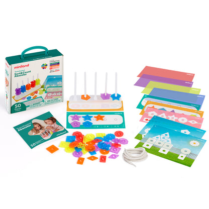 Miniland Translucent Sort & Count Abacolor set with teal carrying case, colorful counting beads, five white pegs, sorting cards with themed scenes, instruction